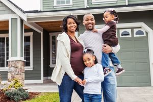 Pregnant family standing outside of their house